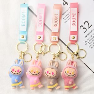 Porte-clés Labubu en peluche – Modèles kawaii (bleu, rose clair, marron, rose foncé) avec bandeau “BOOM!” pour fans Labubu en France